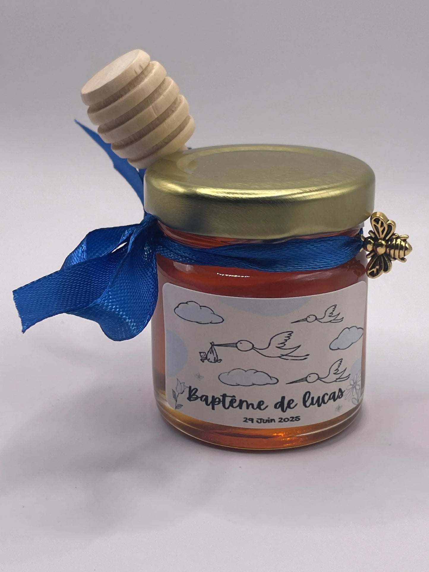 Petit pot de miel personnalisé pour baptême avec étiquette 'Baptême de Lucas', ruban bleu et cuillère en bois