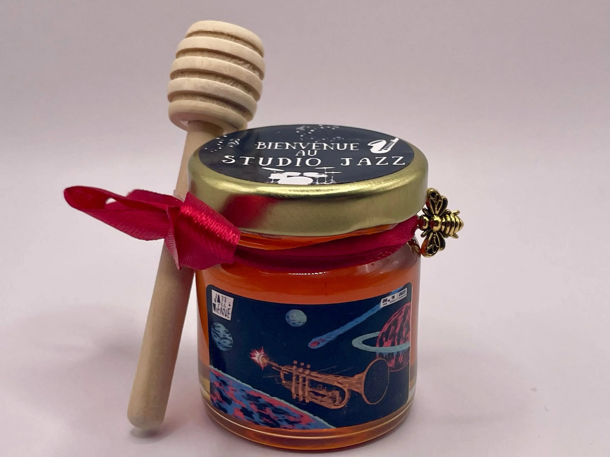 Petit pot de miel personnalisé 'Bienvenue au Studio Jazz' avec cuillère en bois et ruban rouge, idéal cadeau invité mariage.