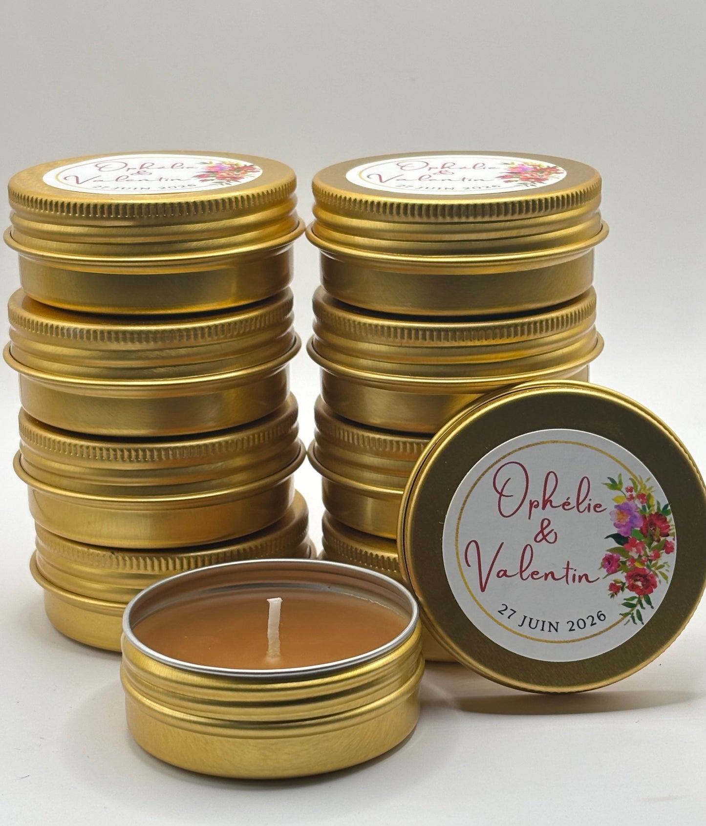 Bougies artisanales en cire d'abeille dans des boîtes dorées personnalisées pour un mariage avec les prénoms Ophélie et Valentin et la date du 27 juin 2026