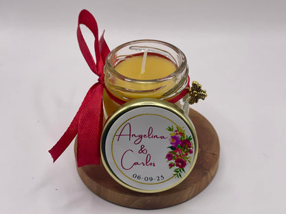 Illuminez votre grand jour avec un cadeau d'invité de mariage original, chaleureux et 100 % naturel. Découvrez notre mini bougie personnalisée, coulée à la main à base de cire d'abeille. Avec son sticker fleuri aux teintes fuchsia éclatantes (modèle Angelina & Carlos), son ruban de satin rouge et son délicat charm d'abeille dorée, c'est le souvenir de mariage parfait qui change des dragées traditionnelles. Une création artisanale et soignée à configurer sur apidelice.fr !